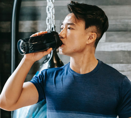 man drinking protein beverage in gym