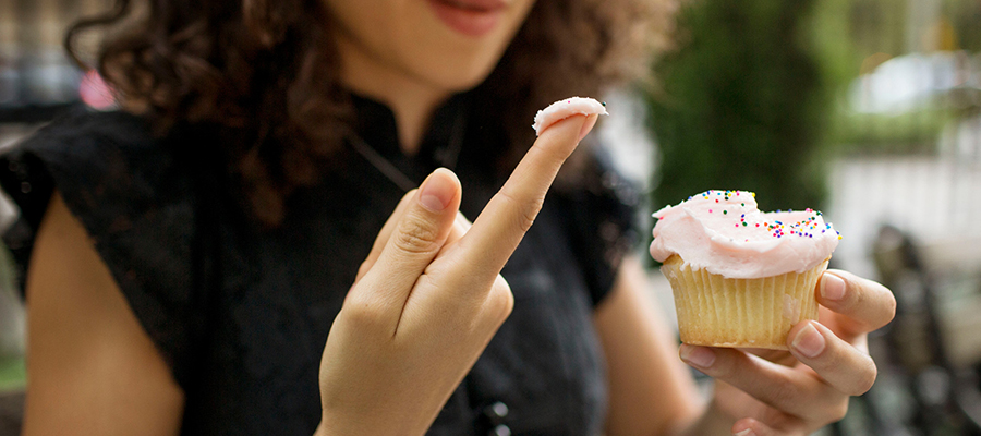 woman holding cupcake and tasting frosting