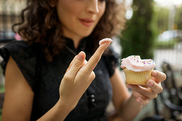 woman holding cupcake tasting frosting