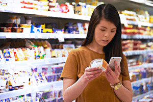 Insights. A consumer looking at a label in a supermarket and checking the ingredients on her phone.